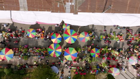 static top down aerial footage of a busy market street in san juan ostuncaclo, guatemala showing a plethora of colorful vendor umbrellas