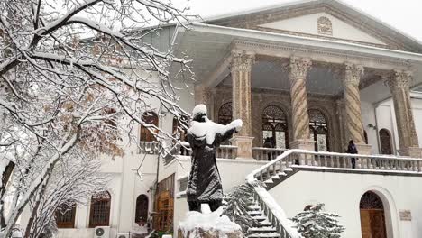 black statue covered by heavy snow in tehran a warm white color traditional historical old house palace in city center with spiral carved marble stone scenic view of architectural design visitor snow