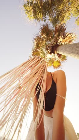 woman with braids under a palm tree