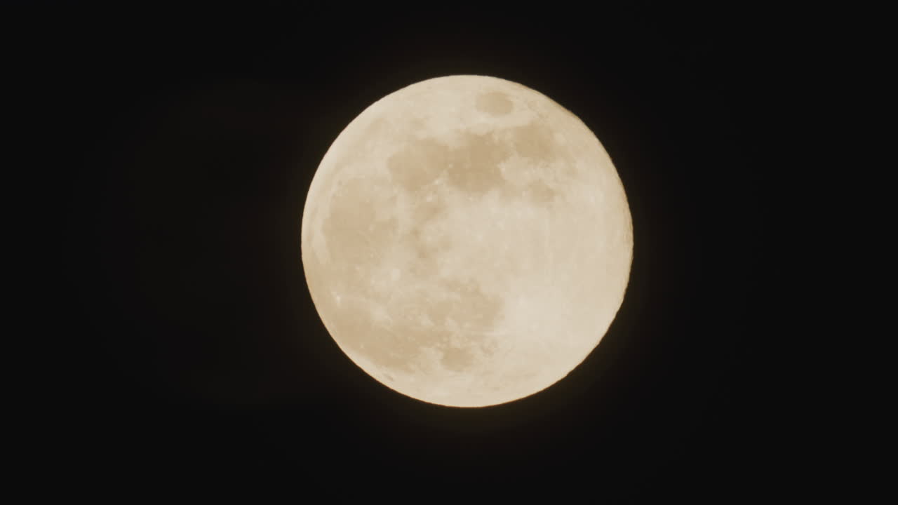 Close-up de uma lua cheia brilhante contra um céu noturno escuro. Textura detalhada da superfície é visível