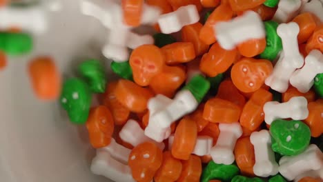 orange and green skulls and bones shaped candy falling on a plate