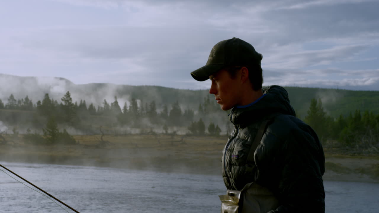 아침 안개 속에서 강을 따라 걷는 어부