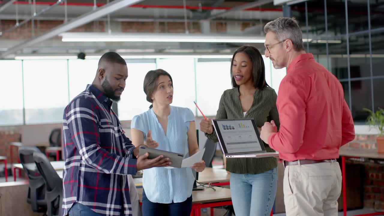 Team of diverse colleagues discussing while standing together at office