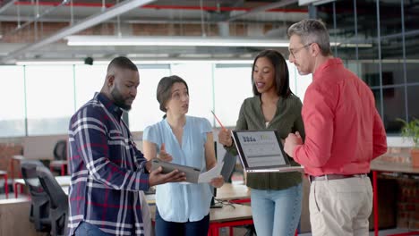 Team-of-diverse-colleagues-discussing-while-standing-together-at-office