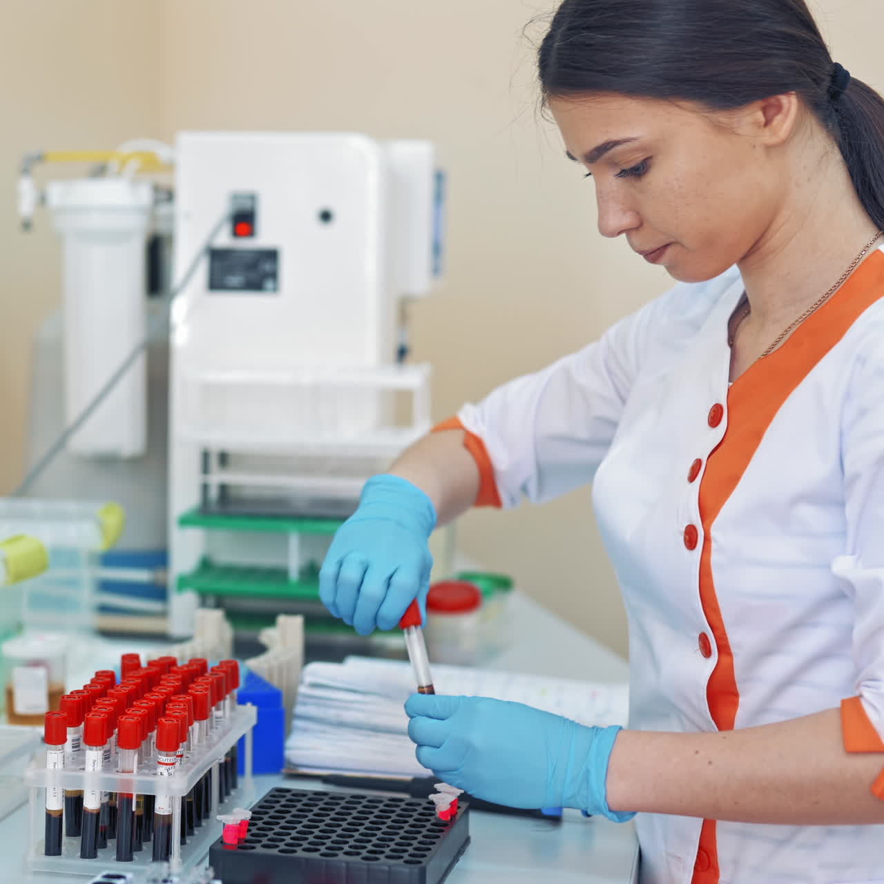 Beautiful laboratory technician woman in medical uniform works with blood samples. Female researcher is working with many vials of liquid in the laboratory.