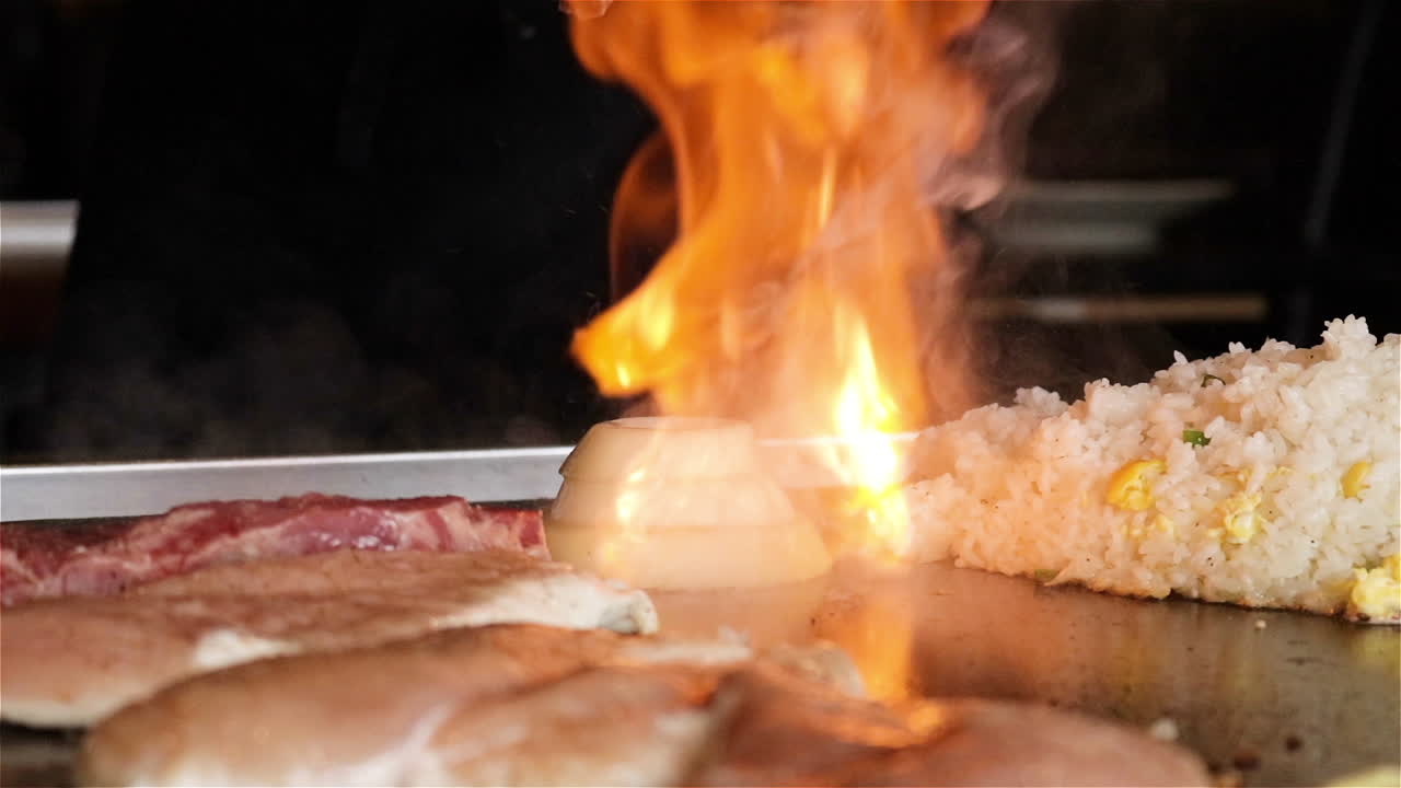 Slow motion shot of a Japanese chef igniting a flaming onion on a flat top grill