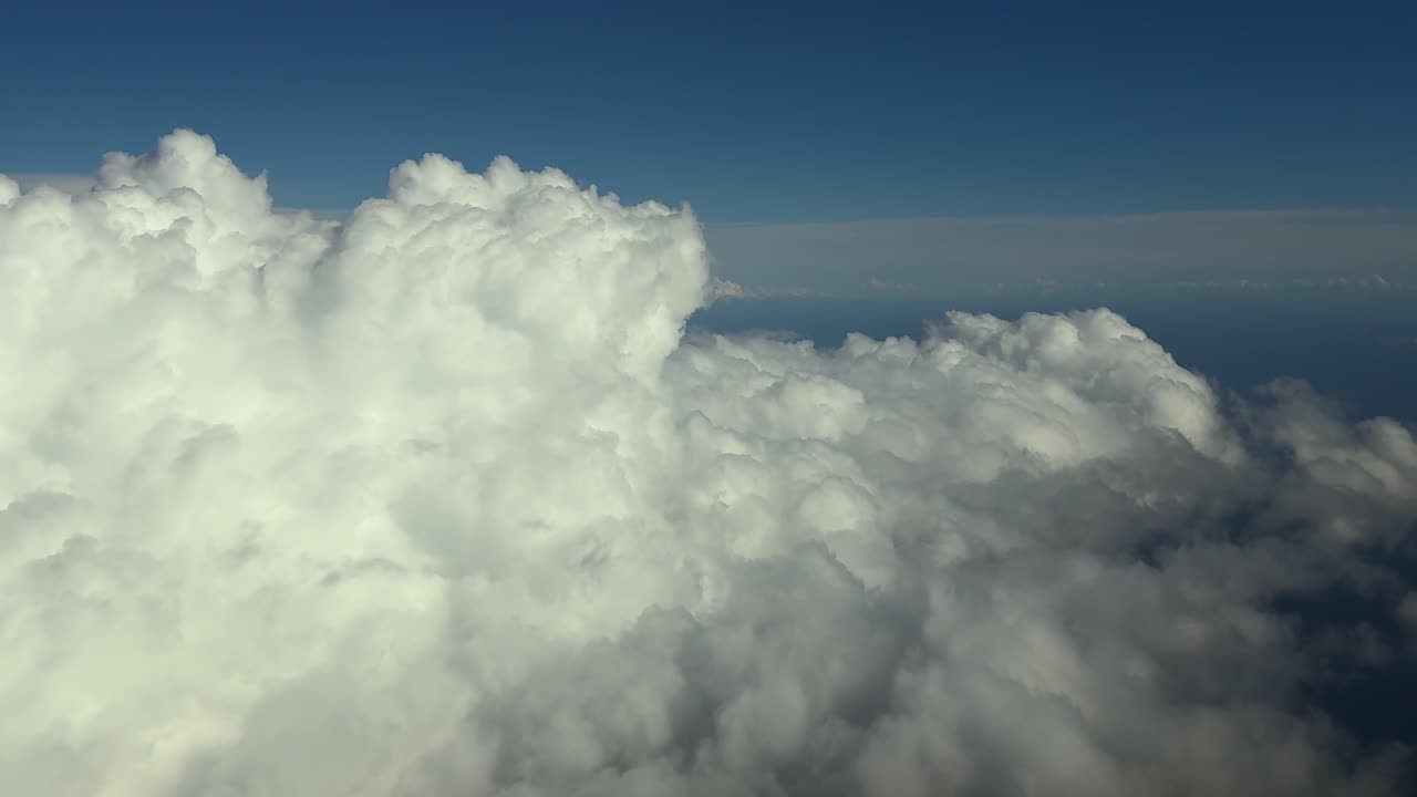 A pilot’s eye view of towering storm cumulonimbus clouds taken from a jet cockpit while flying at the blue hour over the Mediterranean Sea