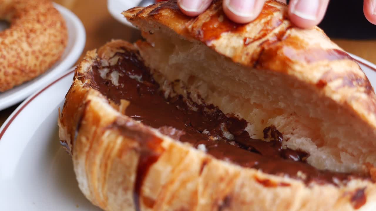 Hand opening a chocolate croissant