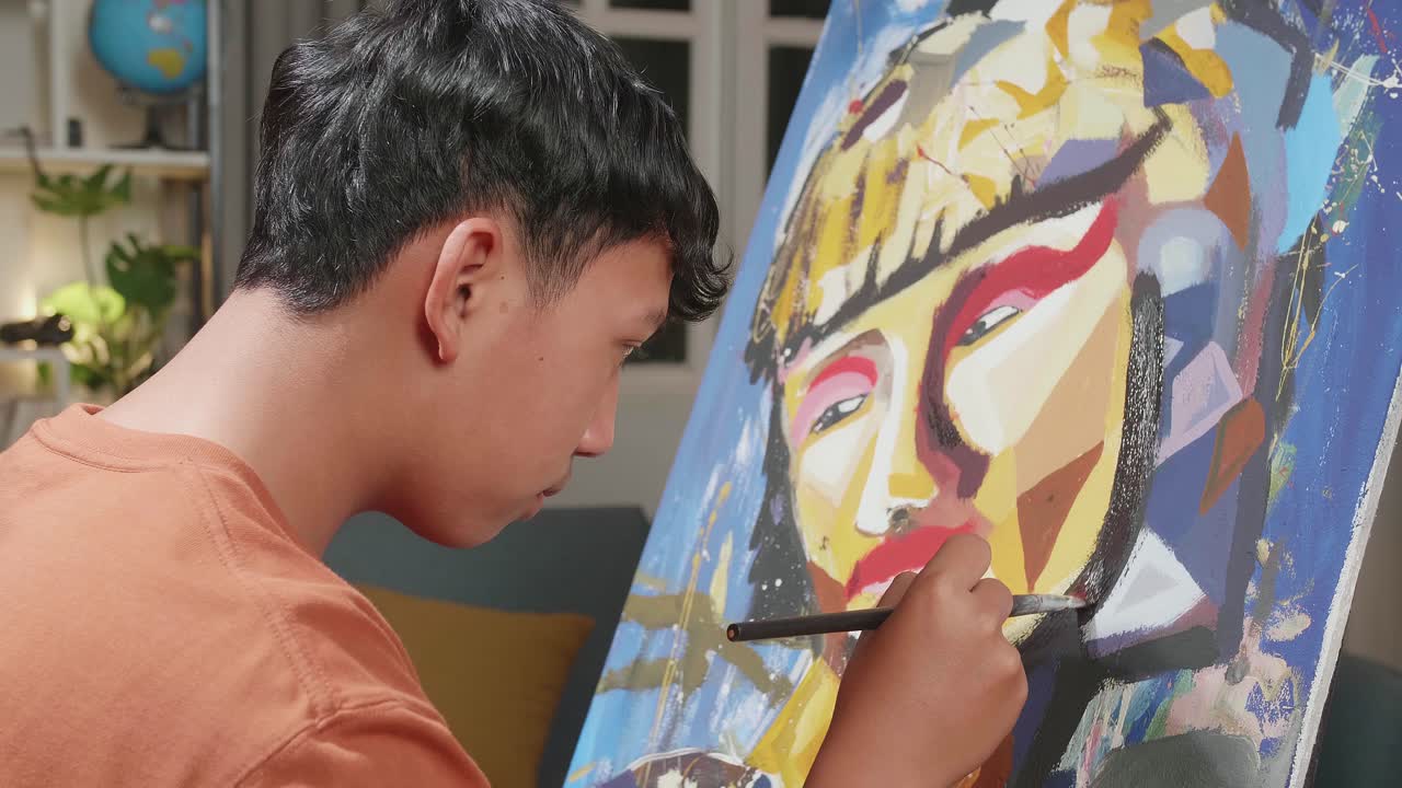 Close Up Side View Of An Asian Artist Boy Holding Paintbrush Mixed Colour And Painting A Girl'S Face On The Canvas