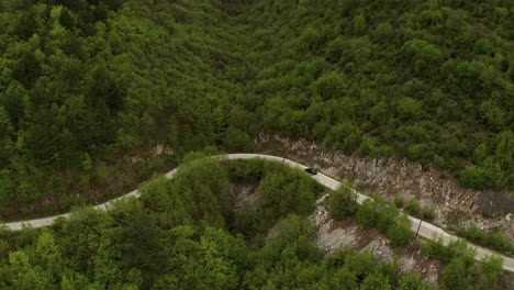 aerial drone flight over curved road into the jungle