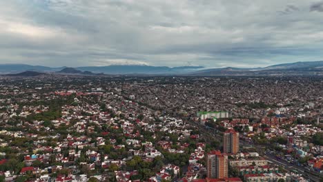 Ascending hyperlapse aerial view of southern CDMX with volcanoes in distance