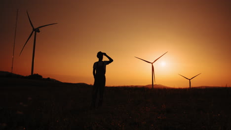 silhouette of a worker at a wind farm during sunset