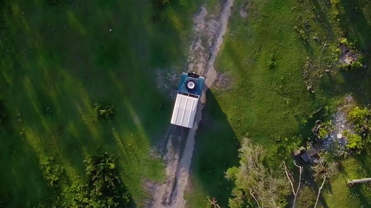 Drone shot low above a blue 4x4 car overlanding on a jungle road, rough terrain, at Cerro El Volcan, El Hatillo, Venezuela - birdseye, aerial view