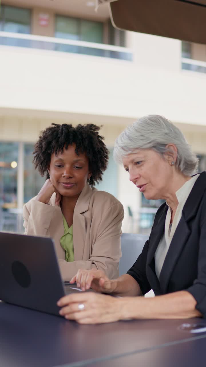 Due donne d'affari che collaborano a un progetto su un portatile all'aperto