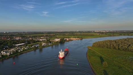 aerial view of cargo ship cruising down a river surrounded by green landscapes