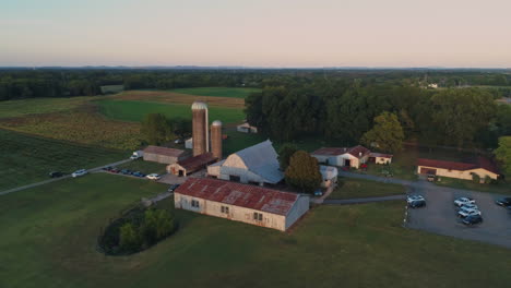 aerial view orbiting barn with grain silos at sunset, 4k