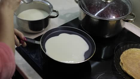 the process of cooking homemade pancakes. woman pours pancake dough on pan