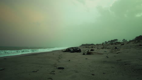 abandoned car carcass on a beach on a dull evening