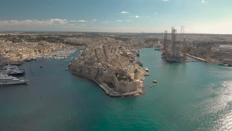 aerial shot towards an old city on a peninsula next to a shipyard