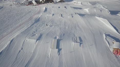 Person-Snowboarding-Down-Slope-Drone-Aerial-View-Above-snowpark---Winter-Extreme-Sports,-Dolomite-Alps-with-snow-in-Madonna-di-Campiglio,-Val-Rendena,-Italian-Alps