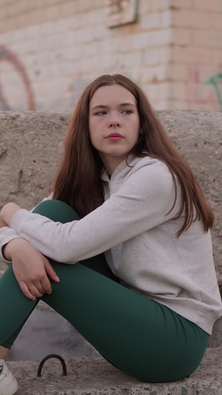 una mujer reflexiona sobre los desafíos de la vida sentada en rocas de hormigón. una mujer considera soluciones a problemas mentales y perspectivas de planes futuros cerca de un edificio abandonado