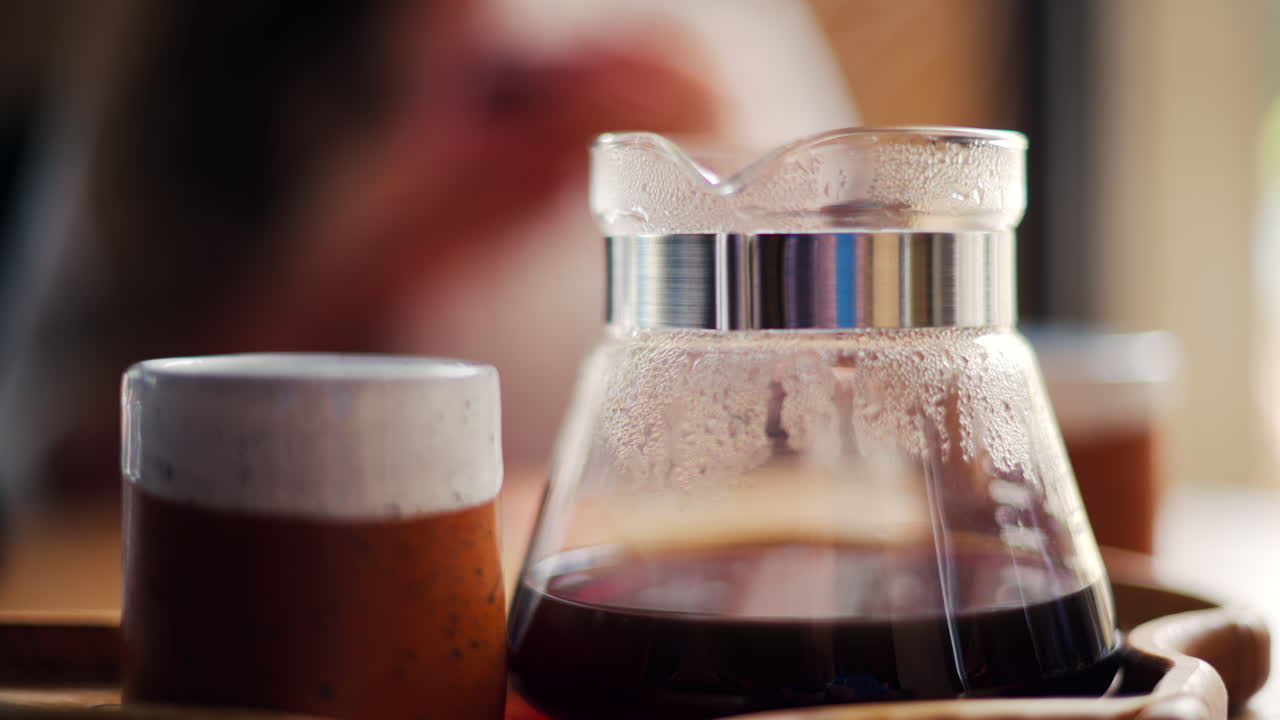 Close up of a glass coffee pot and a cup standing on a wooden tray