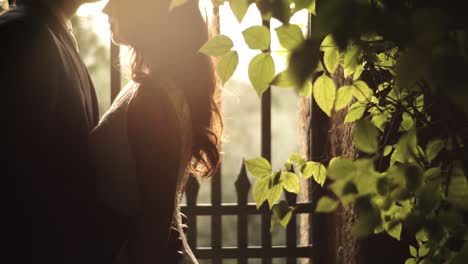 wedding-couple-kiss-in-front-of-a-gate-and-leaves-with-sunset