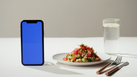 healthy salad with water and smartphone