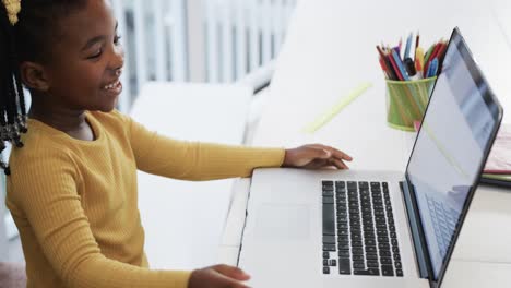 happy african american girl using laptop raising hand in online class, slow motion
