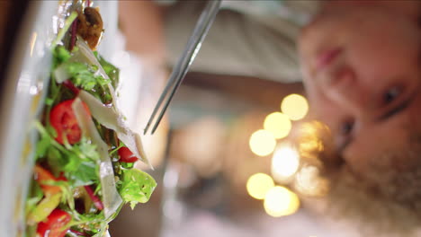 man adding cheese to salad with tweezers