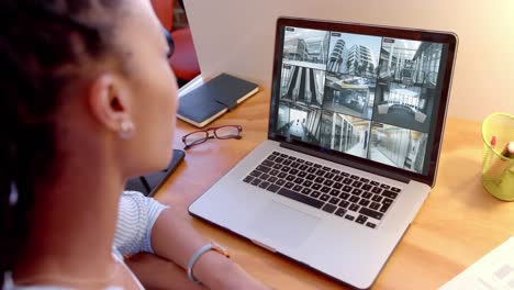 african american female security officer watching business cctv camera views on laptop, slow motion