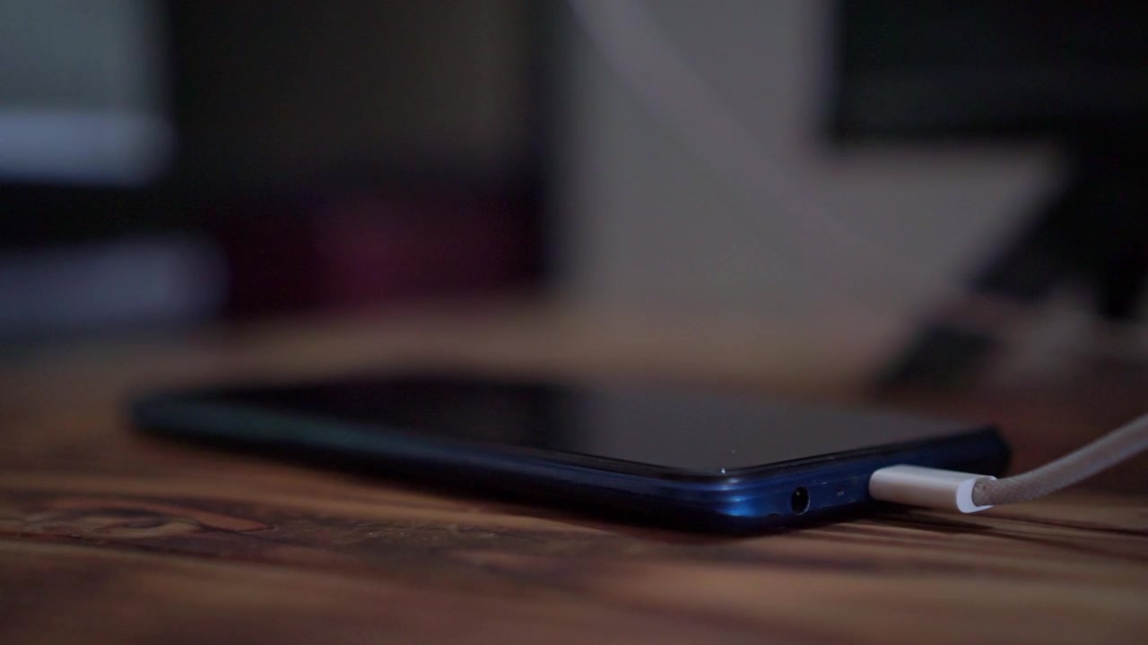 Mano che inserisce il cavo di ricarica nel telefono cellulare, vista ravvicinata, tecnologia di ricarica per smartphone, scena filmata con sfondo scuro