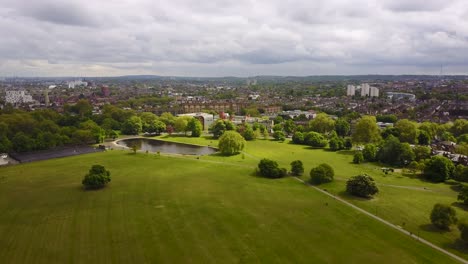 reversing reveal over the lush green grass and a duck pond in clapham common