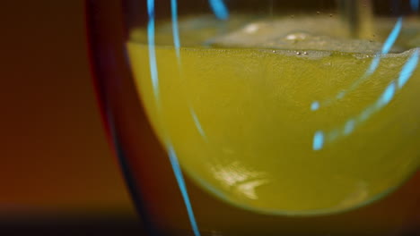 close-up of a bubbly drink in a glass against a green background