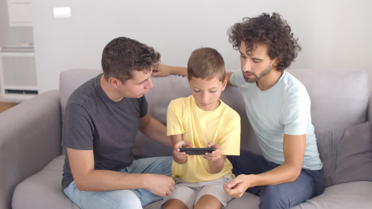 Due papà che aiutano il figlio a giocare a un gioco online o a usare un'app