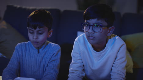 Vista-Frontal-De-Dos-Niños-Pequeños-En-Casa-Divirtiéndose-Jugando-Con-La-Consola-De-Juegos-De-Computadora-En-La-Televisión-Sosteniendo-Controladores-A-Altas-Horas-De-La-Noche-4