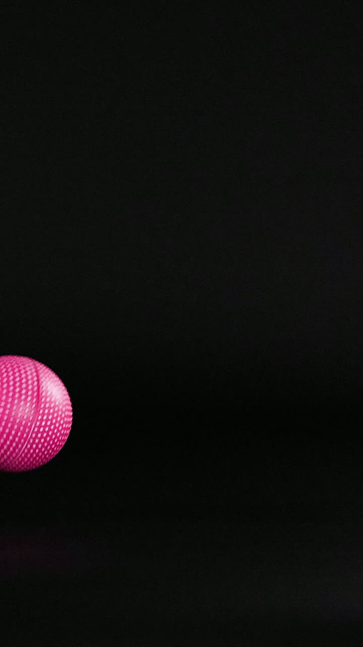 A pink ball moves across a dark background