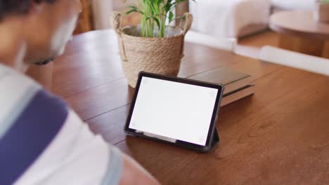 african american man sitting at table and using tablet with copy space for video call, slow motion