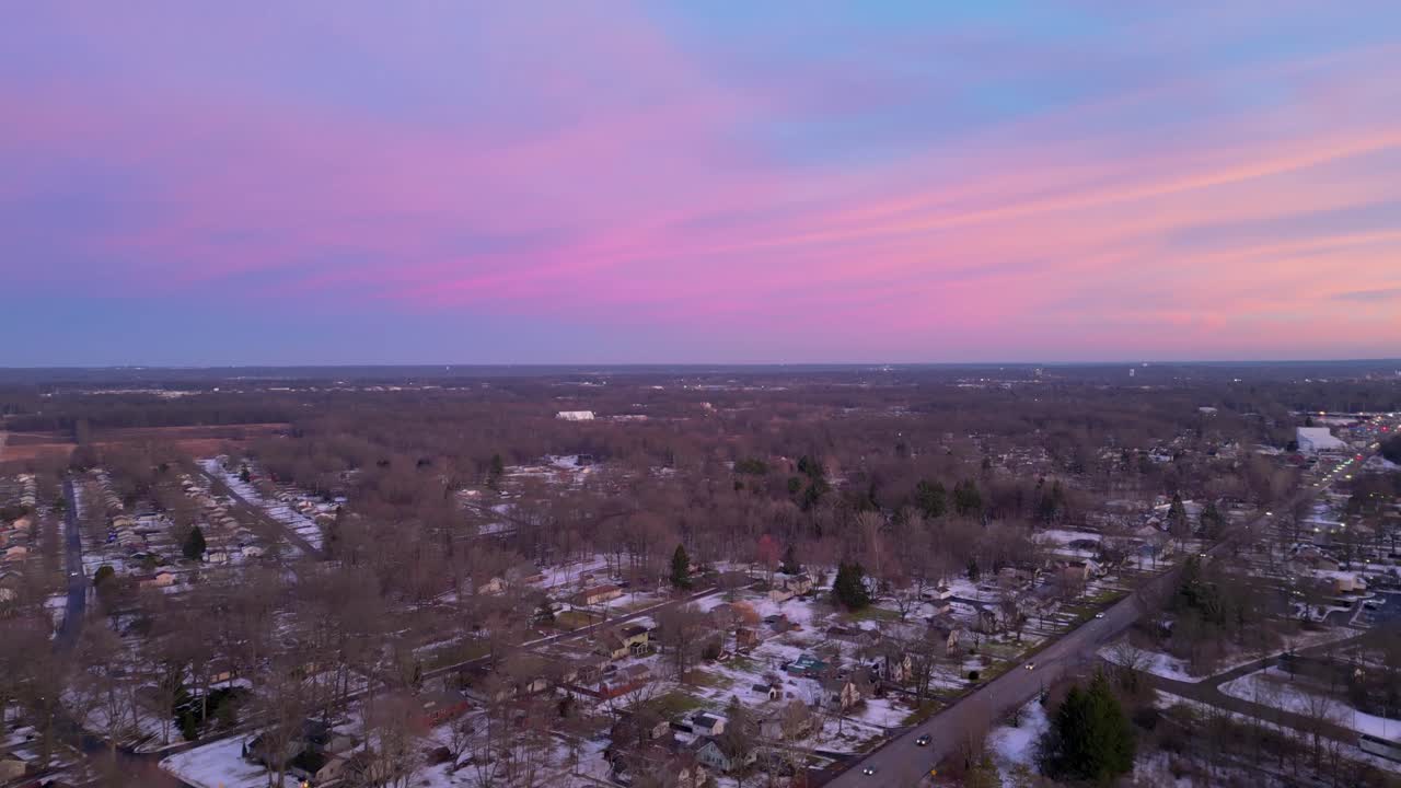 un paisaje suburbano bajo un cielo crepúsculo pintado en tonos rosados y púrpuras, capturando la transición pacífica del día a la noche