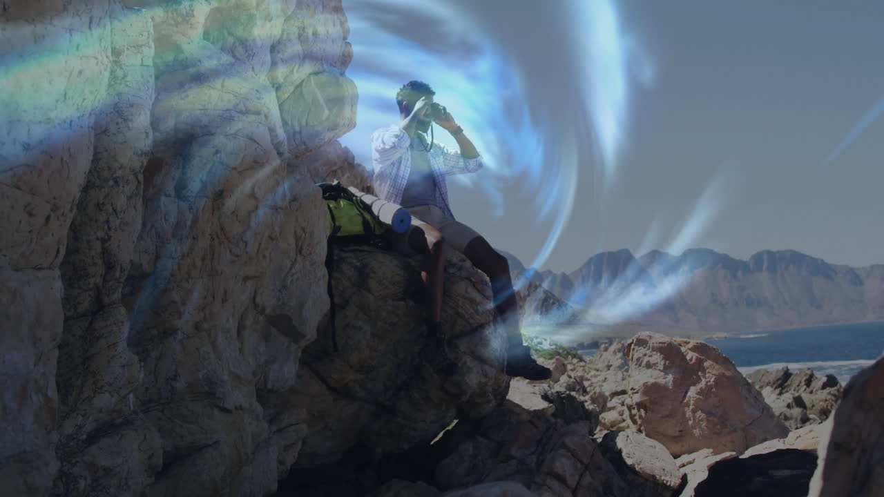 Man sitting on coastal cliff using binoculars, exploring animated technology portal around him