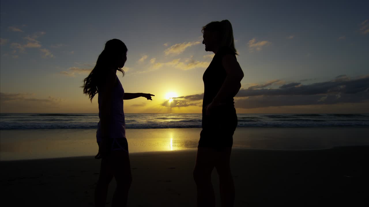 스포츠 시계를 들고 해변에서 달리는 아시아 여성들