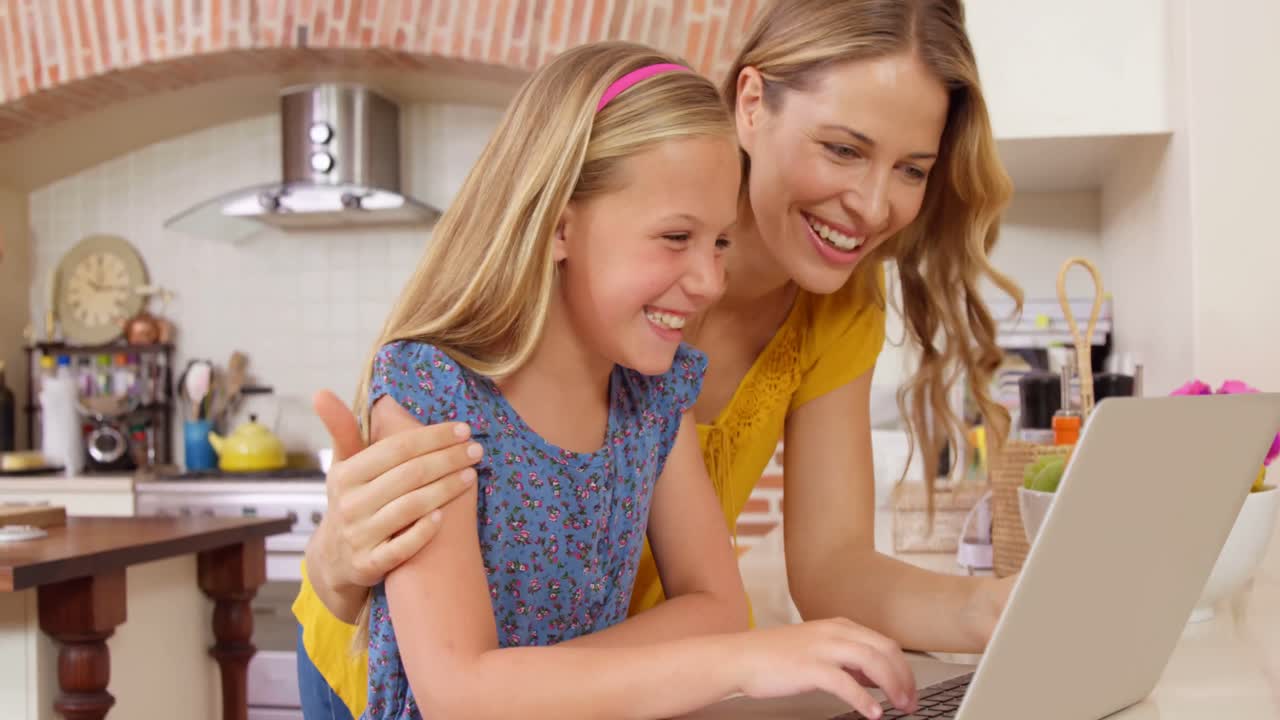 Smiling mother and daughter using laptop