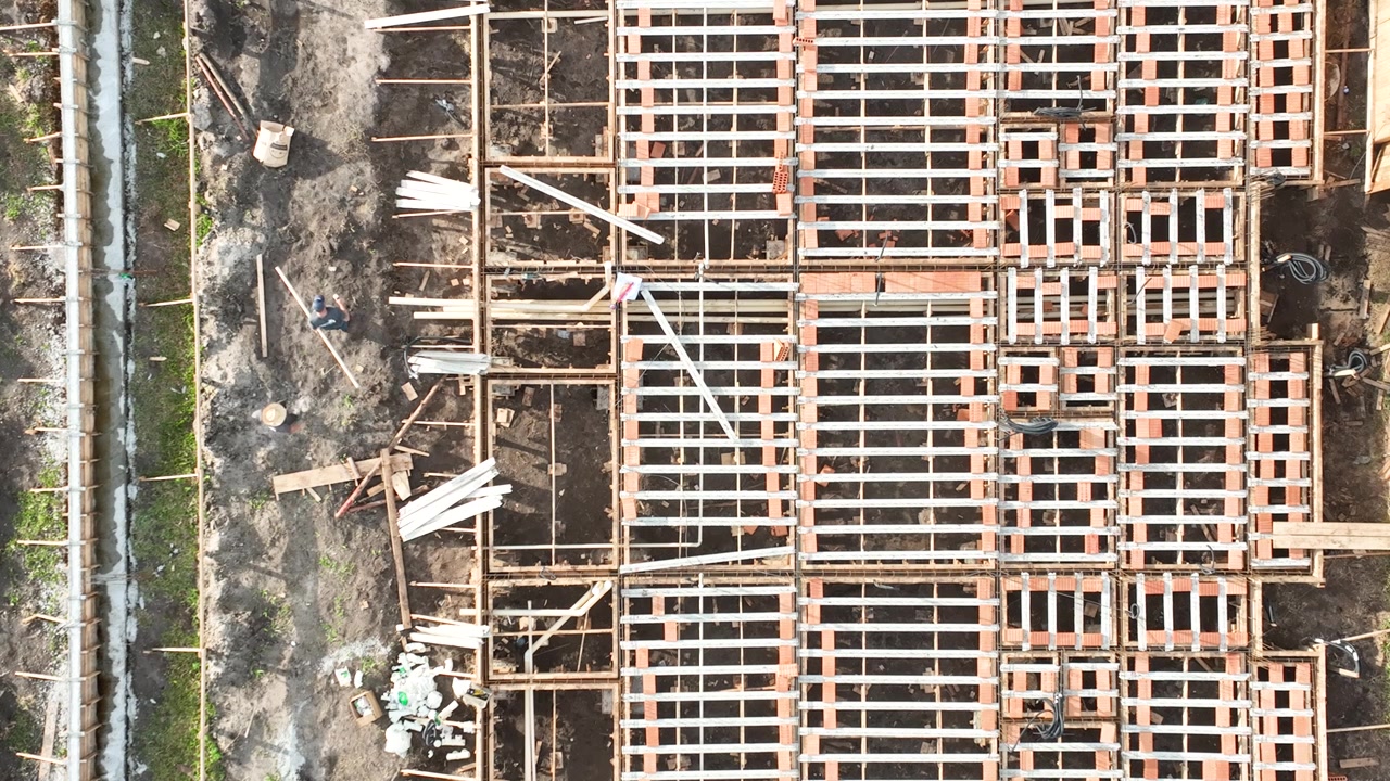 Aerial view of modern residential houses under construction using precast concrete elements with workers on site in Brazil.