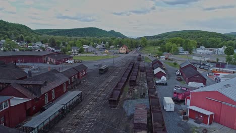 an aerial view of an abandoned narrow gauge coal rail road with rusting hoppers and freight cars and support building starting to be restored