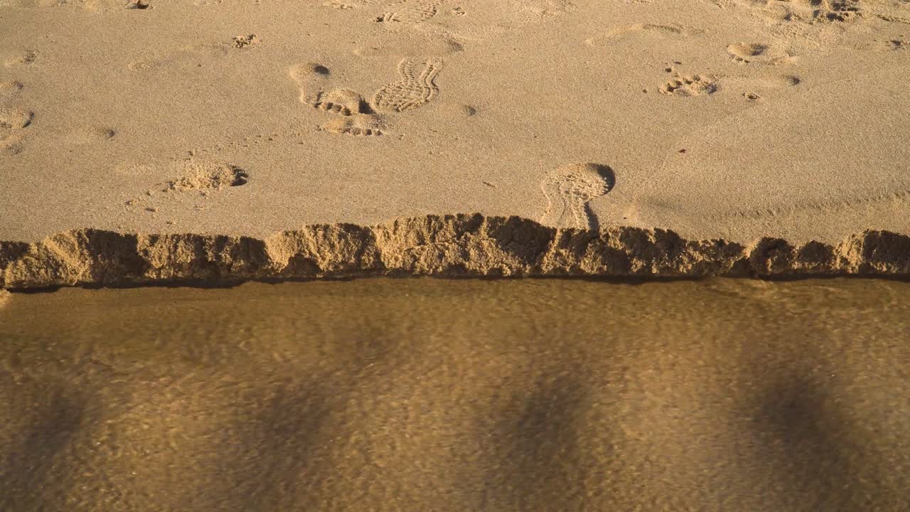 물이 바다로 흘러들어가면서 폭우가 내린 후 해변에서 4k 해안 모래 침식