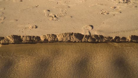 4k-Küstensanderosion-Am-Strand-Nach-Starkem-Regen,-Als-Wasser-Ihren-Weg-In-Den-Ozean-Bahnte