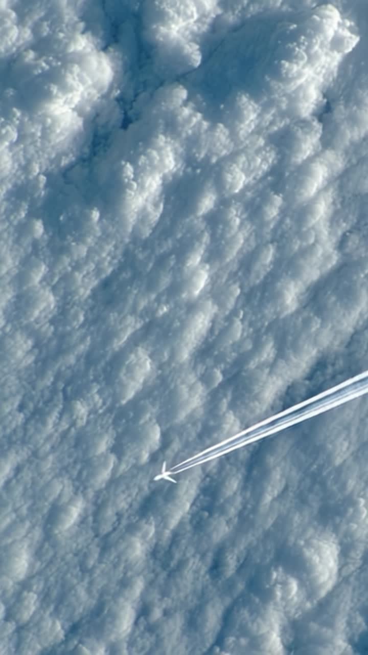 Luftrejse med et fly over stratuskyer med kondensstriber, fanget fra et forhøjet perspektiv under en klar blå himmel
