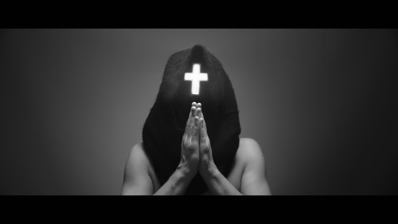 Masked man with cross of light glowing on his face prays