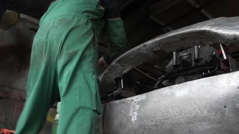 LOCKED-OFF-LOW-ANGLE-view-of-Mechanic-checking-front-body-work-on-car