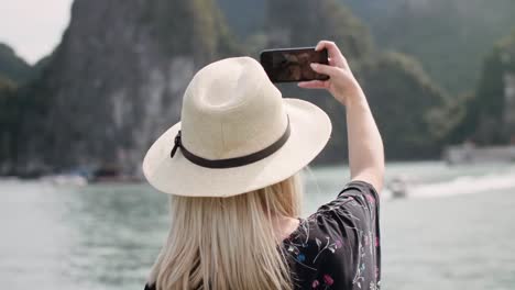 Handheld-view-of-female-tourist-with-mobile-phone-making-selfie